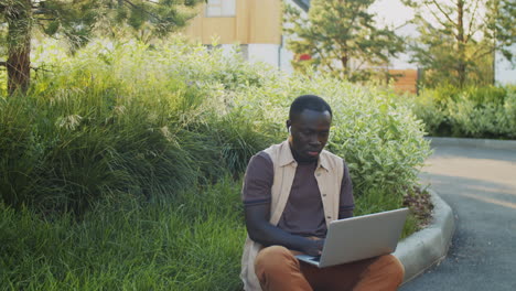 Afroamerikanischer-Mann,-Der-Online-Am-Laptop-Im-Park-Arbeitet